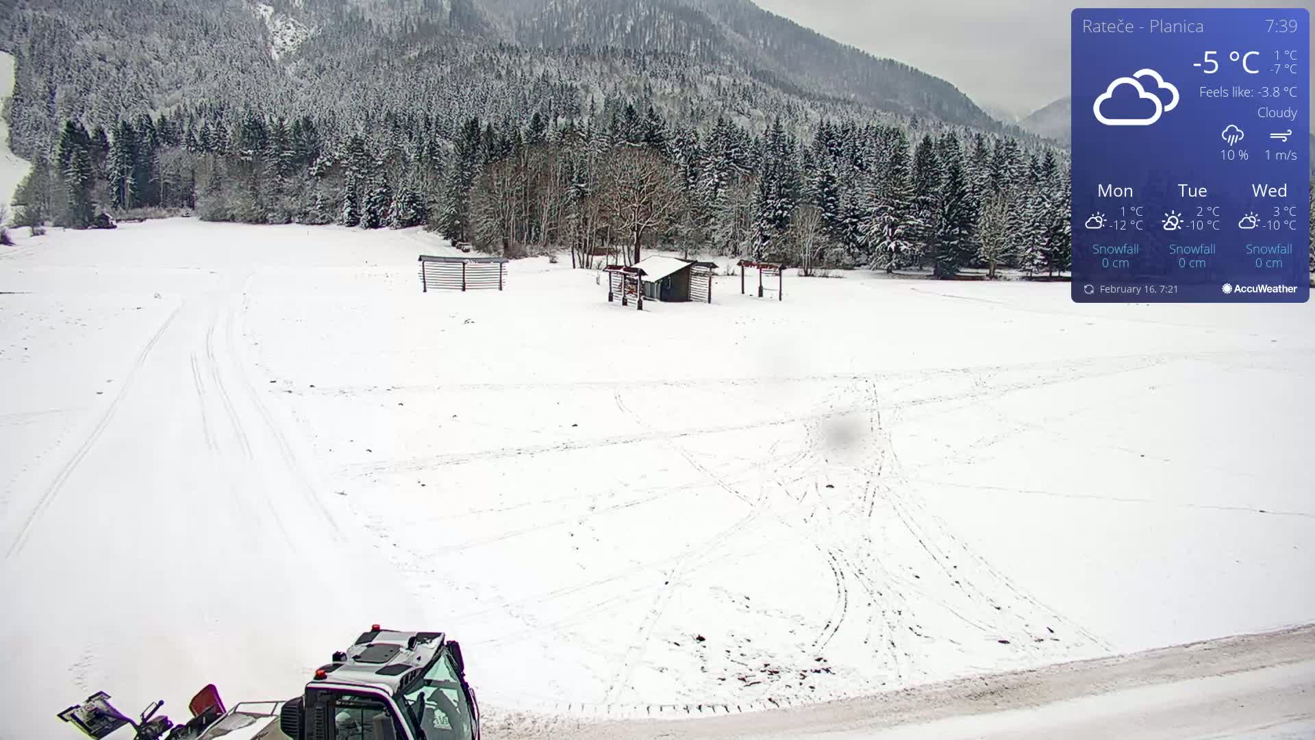 A snow-covered landscape with a snow groomer in the bottom right corner, under cloudy skies.