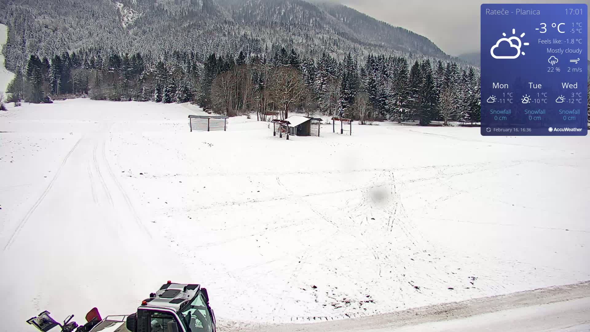 A snow-covered field with a small building and a snowplow is visible, under mostly cloudy skies.
