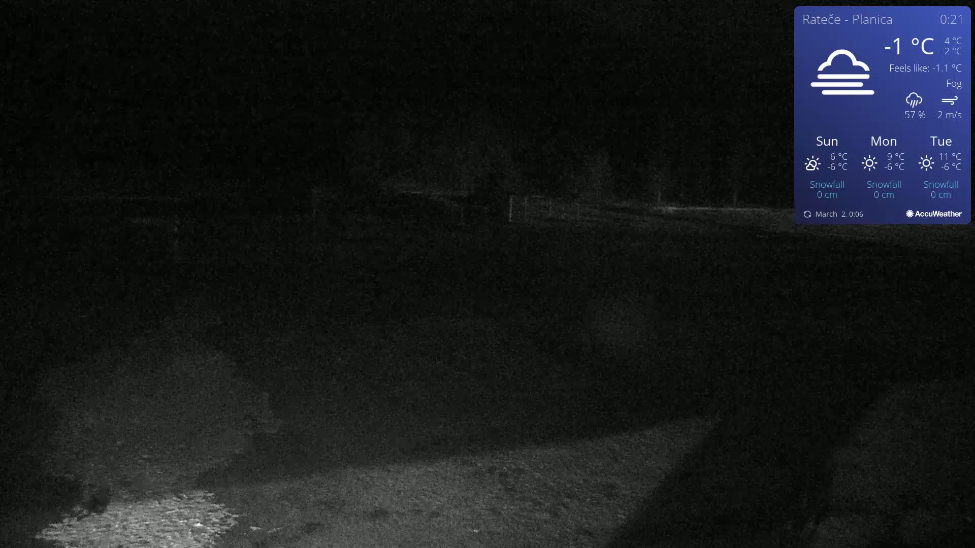 A dark, nighttime outdoor scene showing a mostly empty field under foggy conditions.