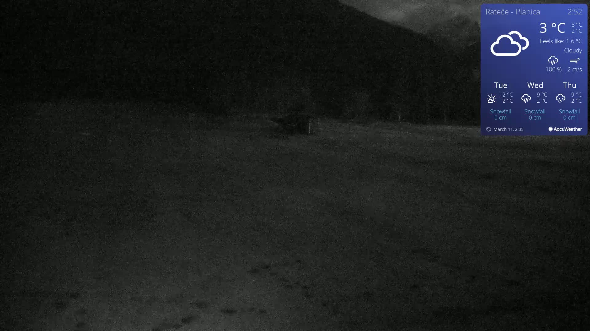 A dark, nighttime outdoor scene shows a snow-covered ground under cloudy skies.