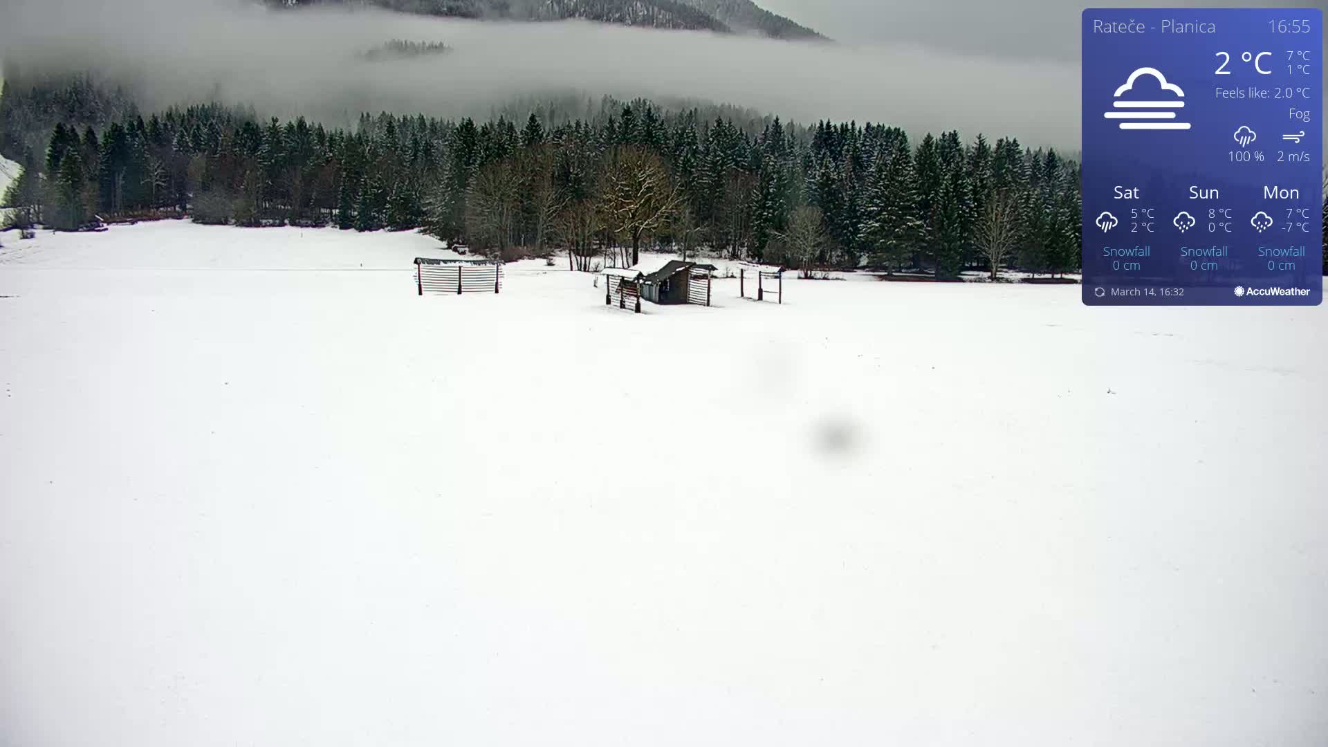 A snow-covered field with a small structure and fencing is visible beneath a foggy sky.