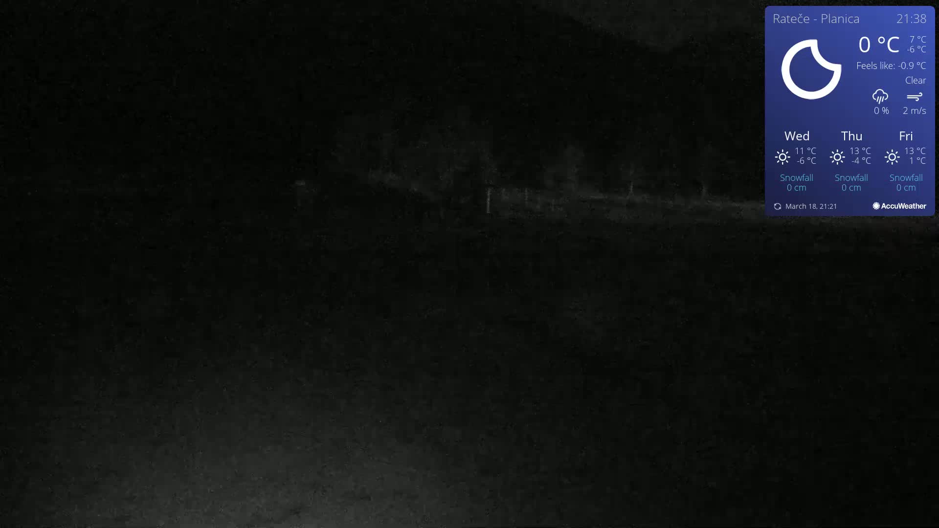 A dark, nighttime outdoor scene shows a mostly clear view of a road and sparse vegetation under a clear sky.