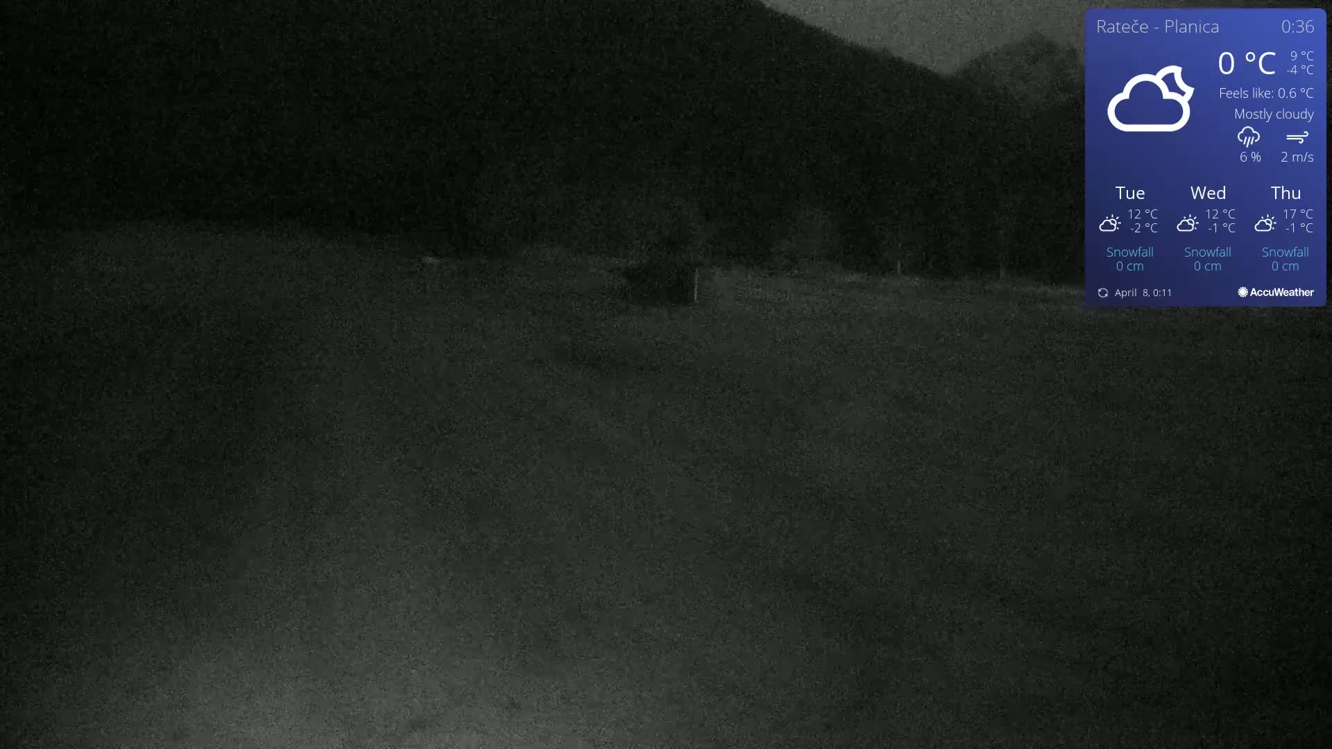 A dark, mostly cloudy nighttime scene shows a flat, dark expanse of land with a hill in the background.