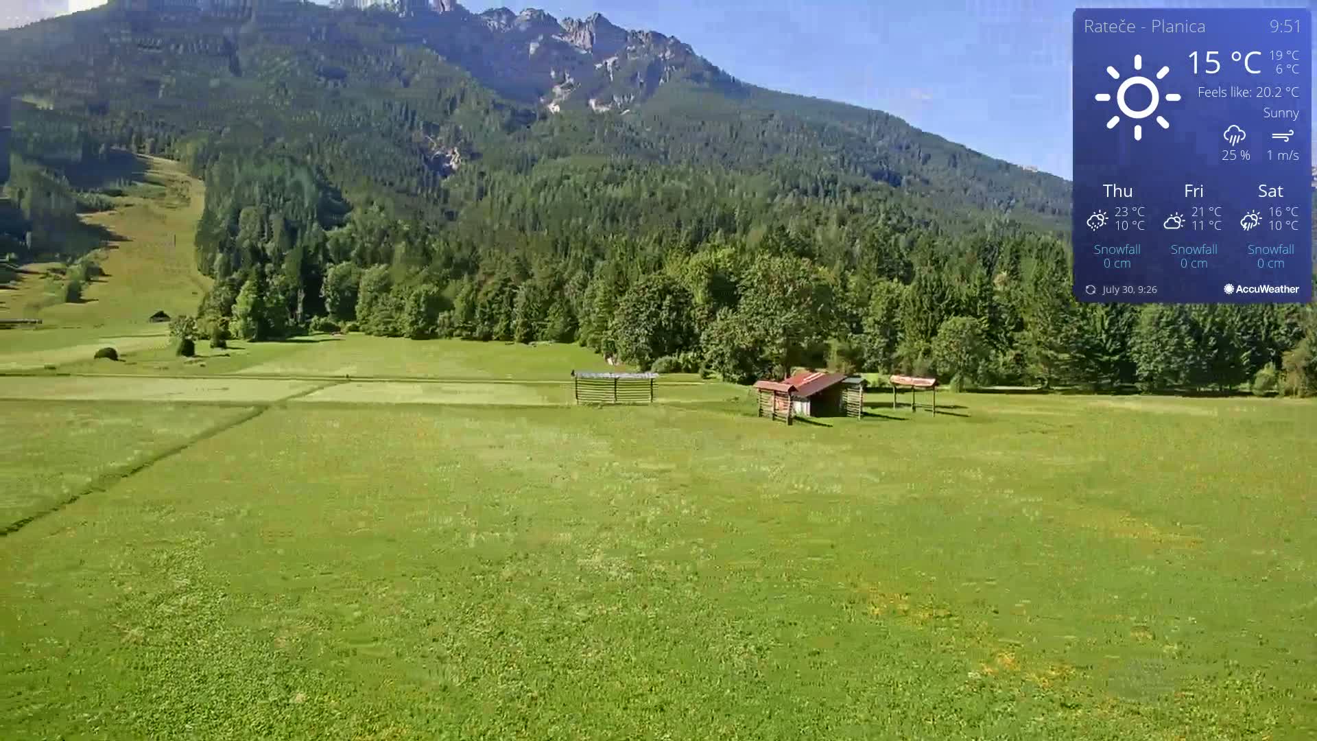 A sunny day in a verdant valley, featuring a small wooden structure and a mountain range in the background.
