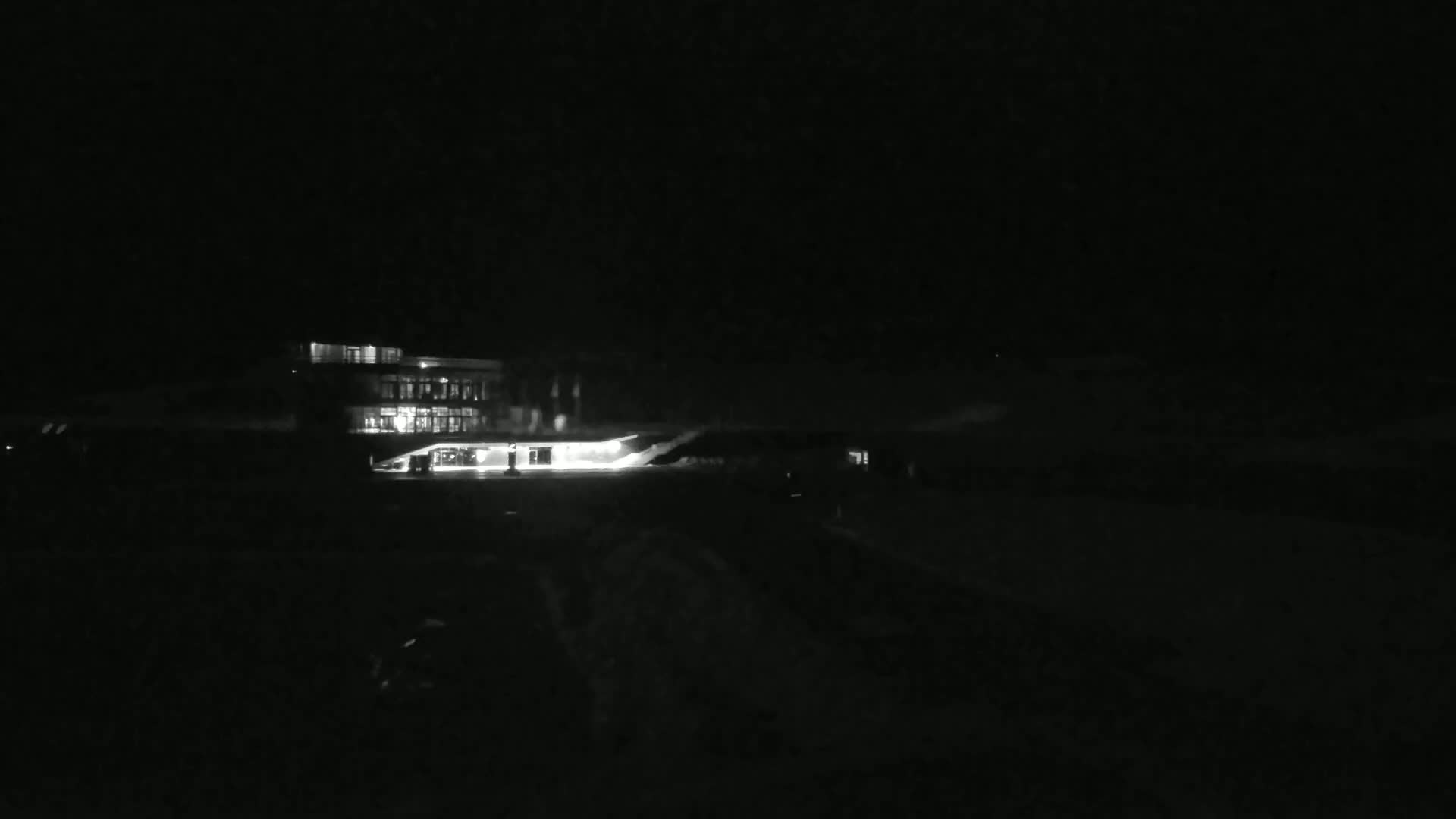 A brightly lit building is visible at night in snowy conditions.