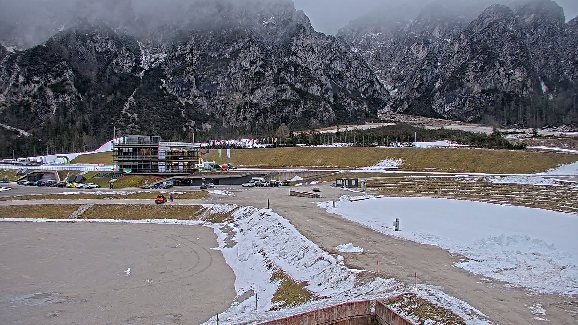 A snowy, overcast day at a winter sports facility situated in a valley between large, rocky mountains.