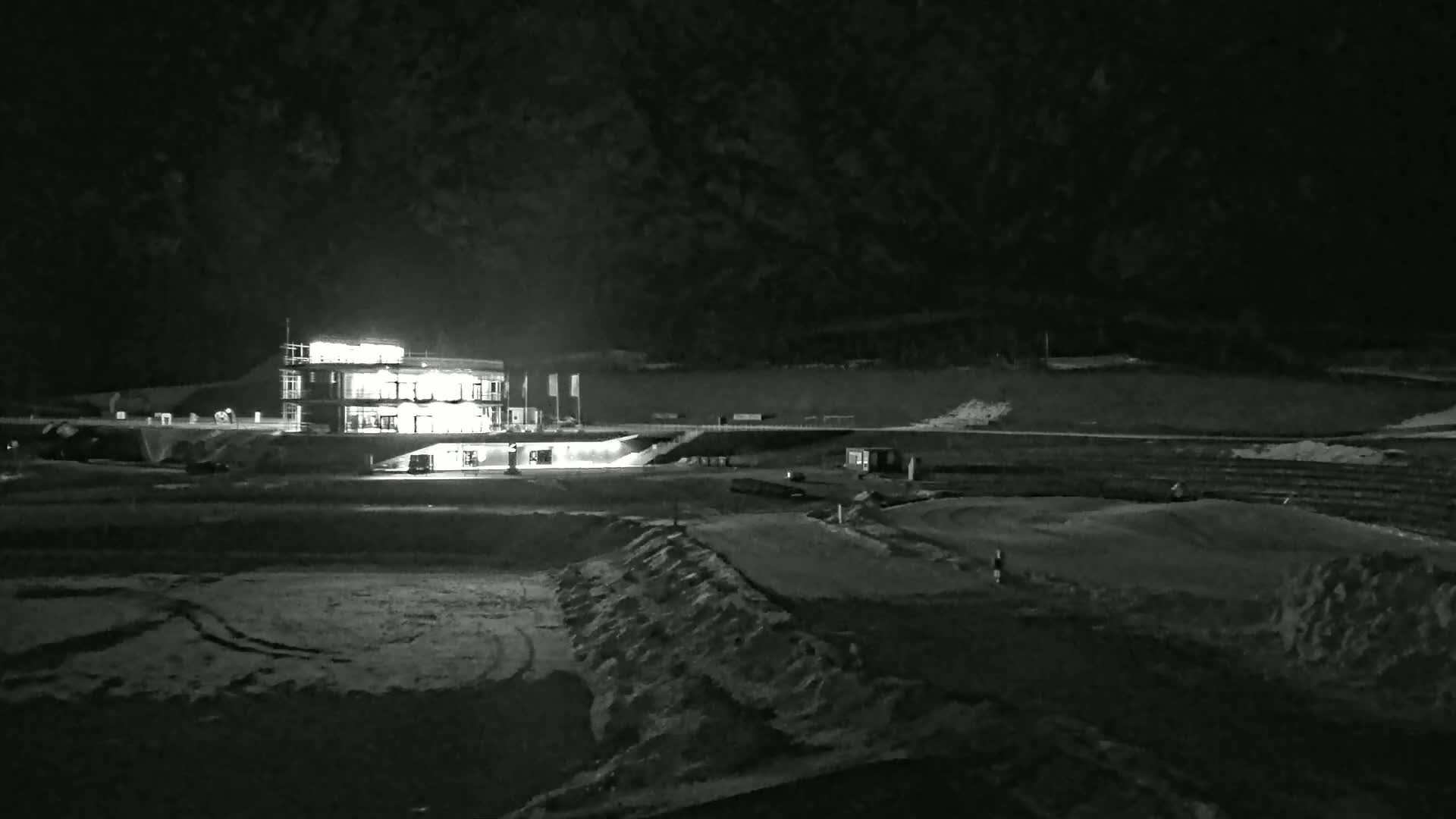 A brightly lit building stands in a snow-covered landscape at night.
