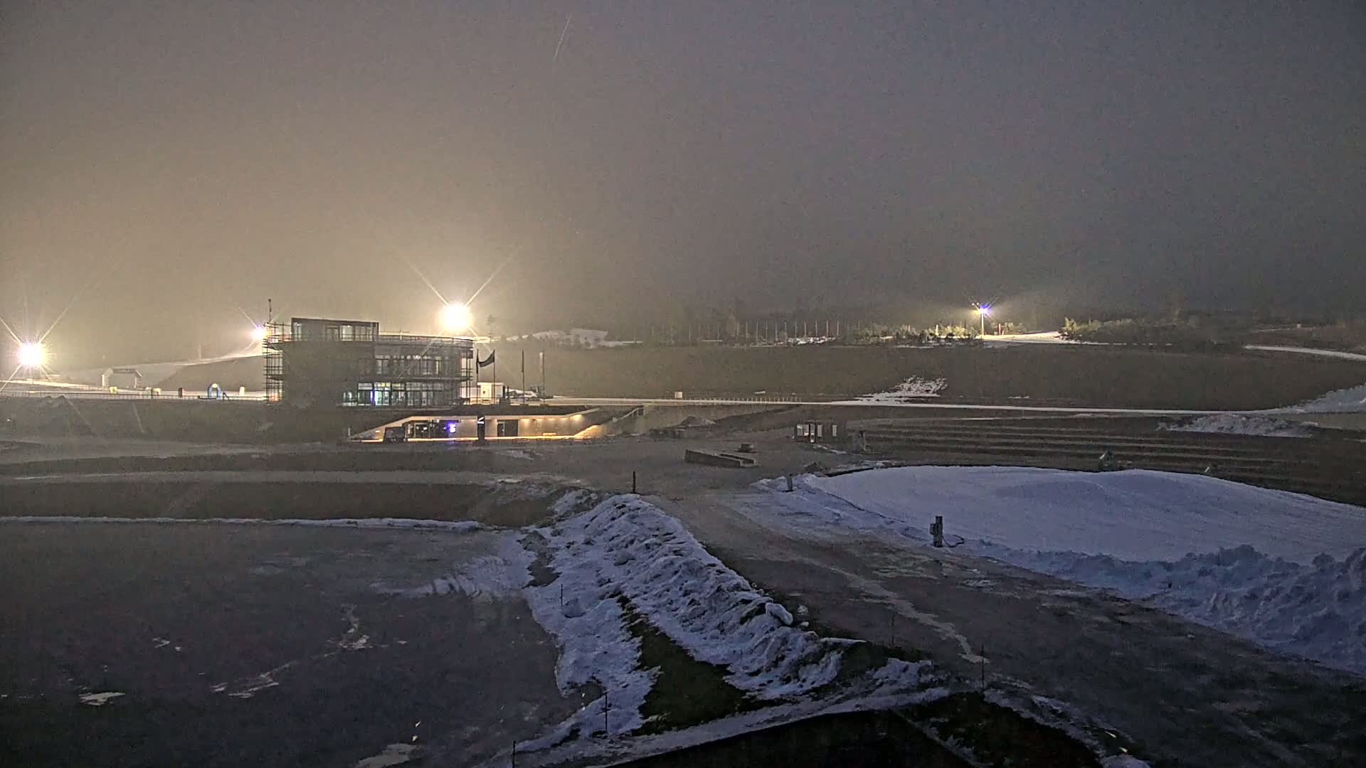 A modern building is illuminated at night in a snowy, foggy landscape.