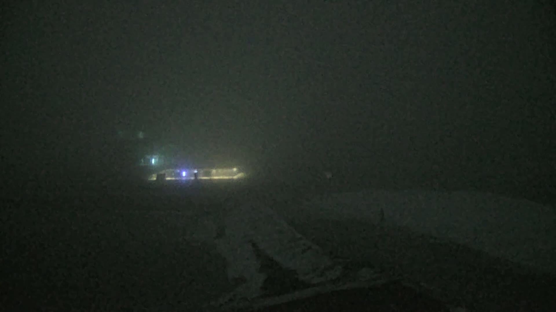 A dimly lit, foggy scene shows a building and a roadway at night.