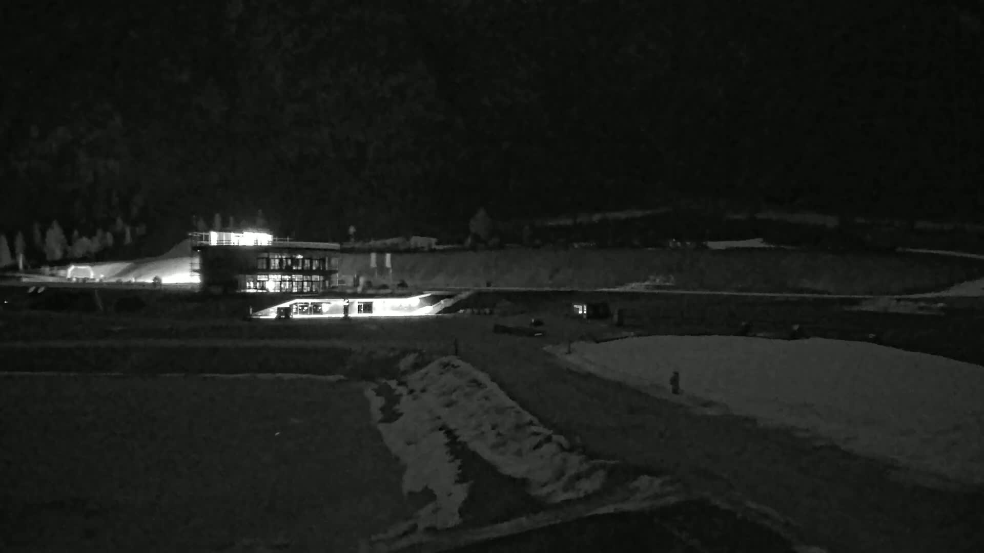 A brightly lit building sits on a snow-covered landscape at night.