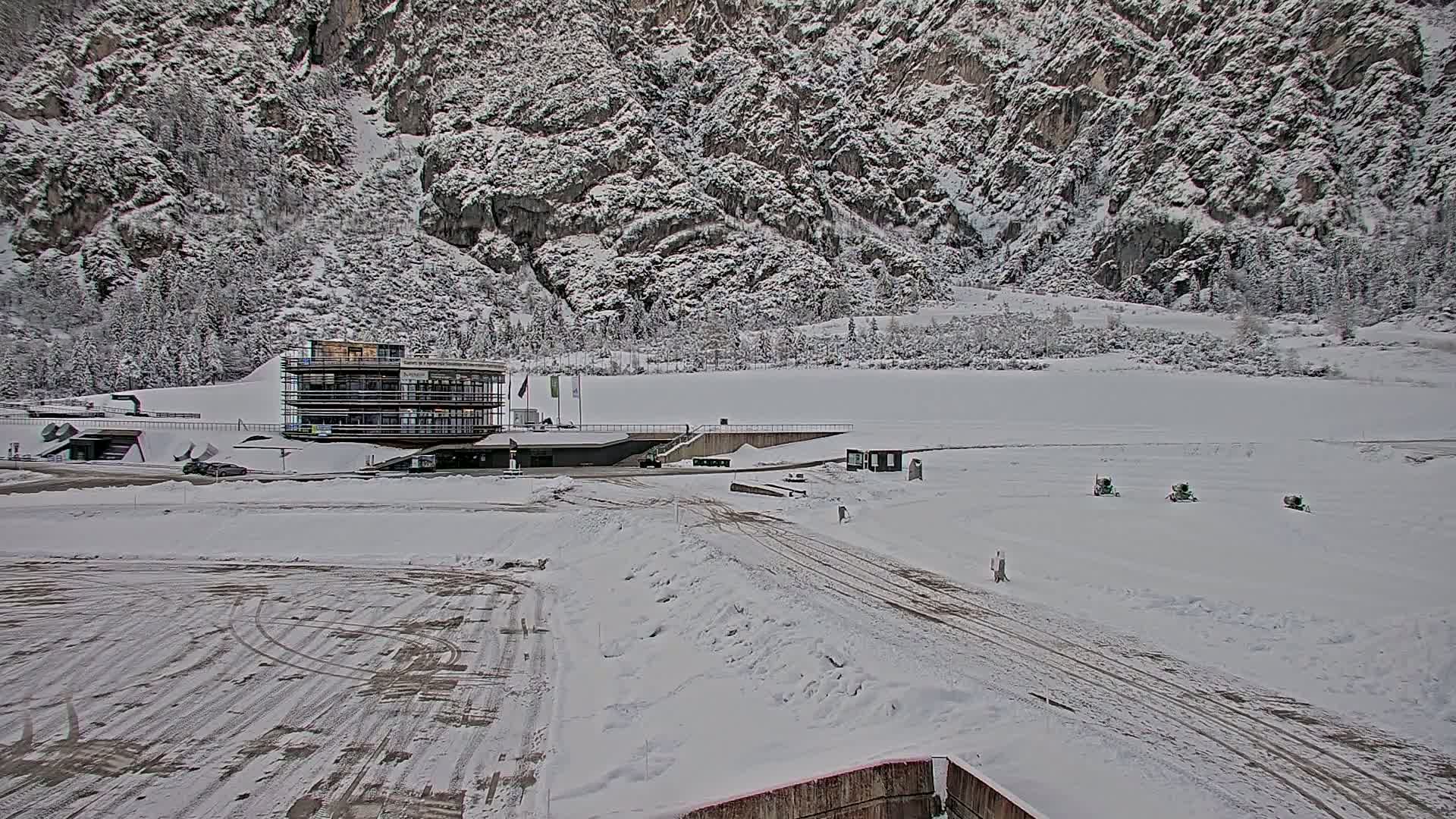 A snow-covered landscape featuring a multi-story building near a rocky, snow-dusted mountain.