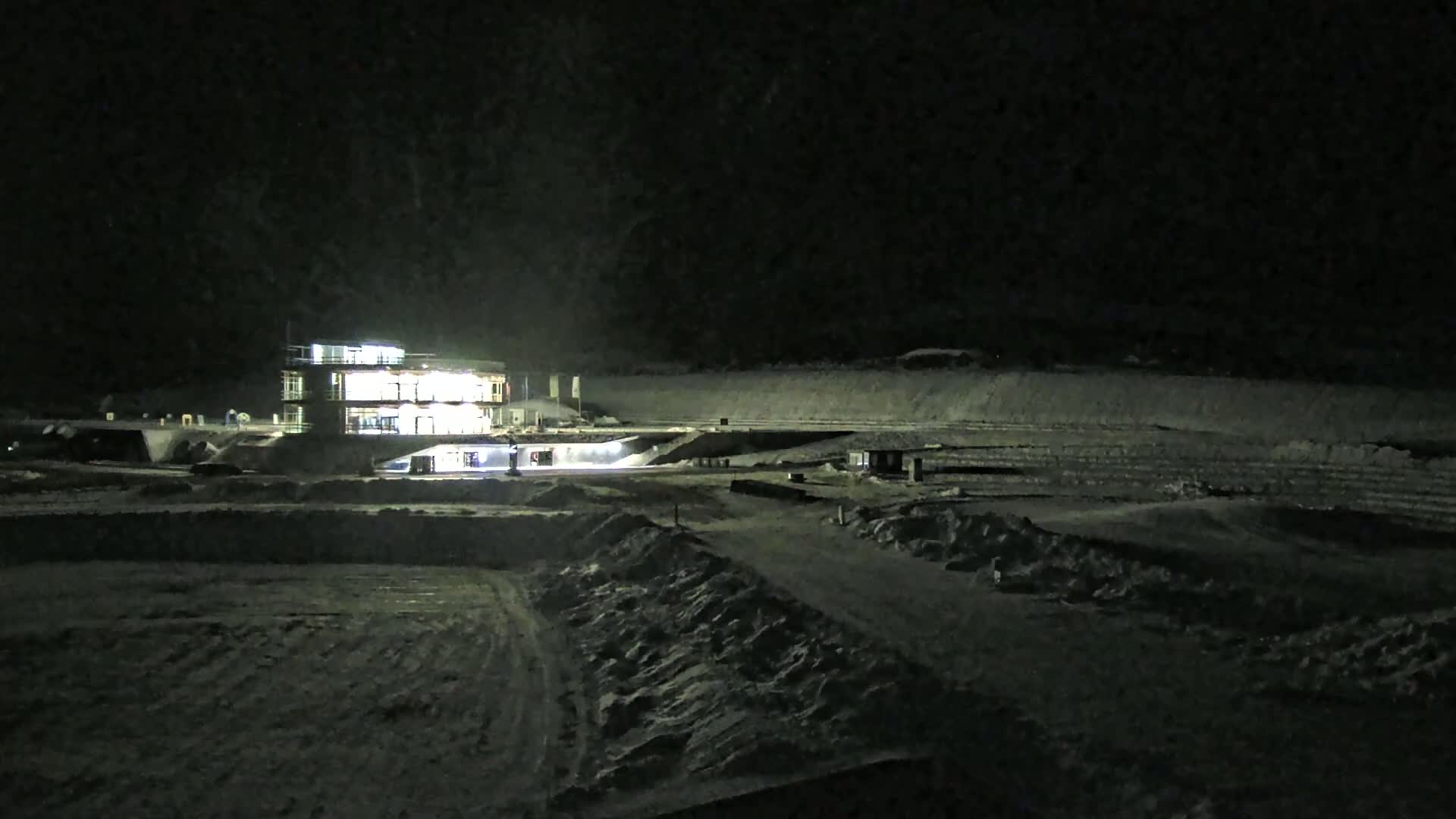 A brightly lit building sits in a snow-covered, outdoor area at night.
