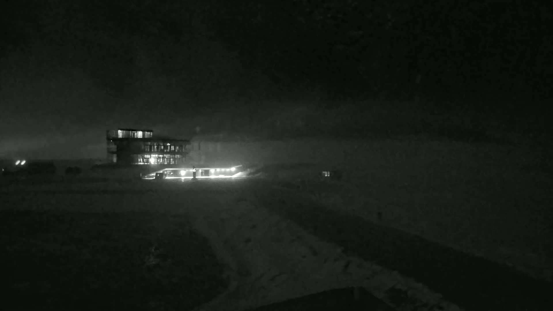 A multi-story building with lights on is visible at night in snowy conditions.