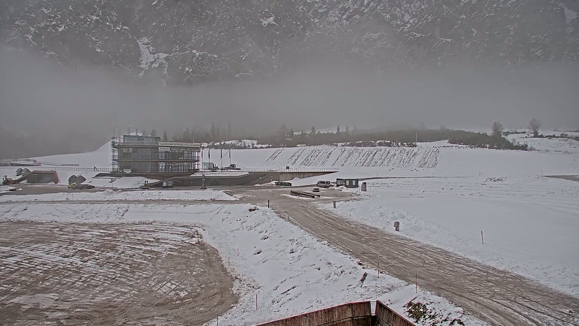 A snowy landscape with a partially-constructed building and a foggy mountain backdrop.