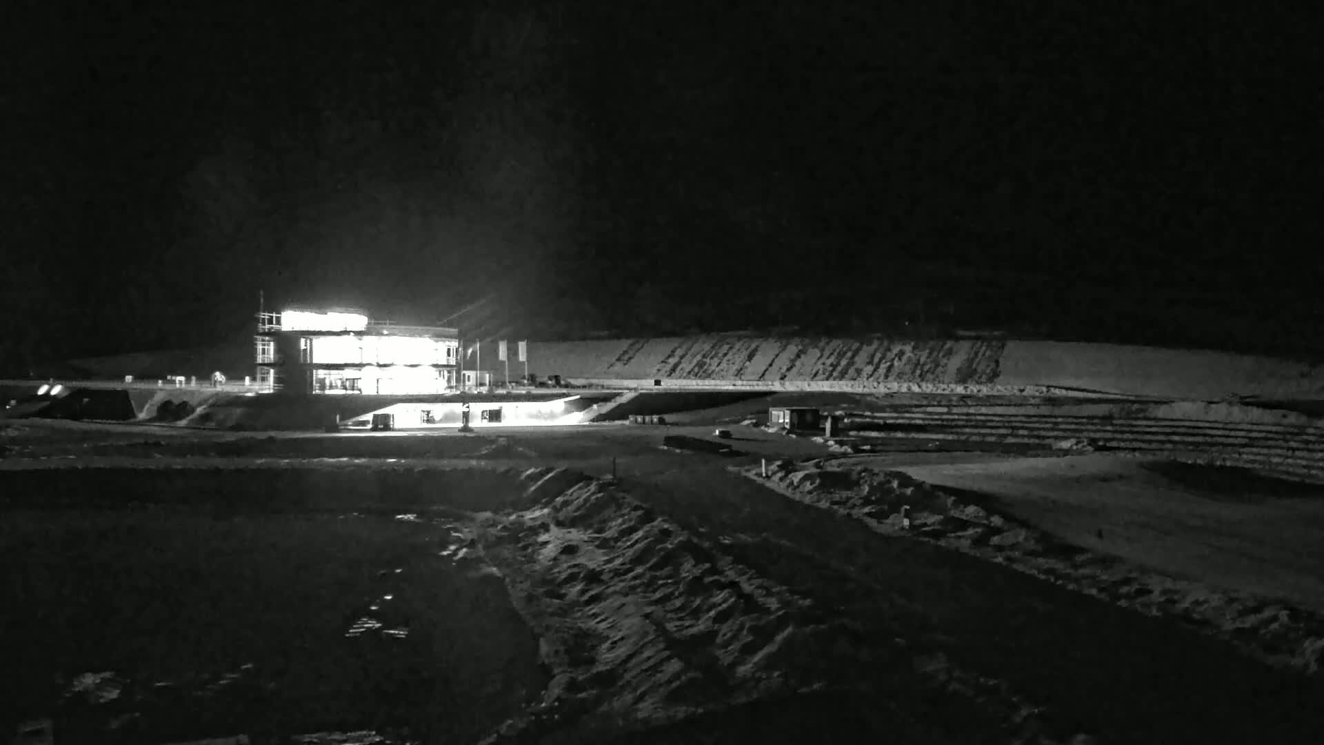 A brightly lit building stands in a snow-covered, nighttime landscape.