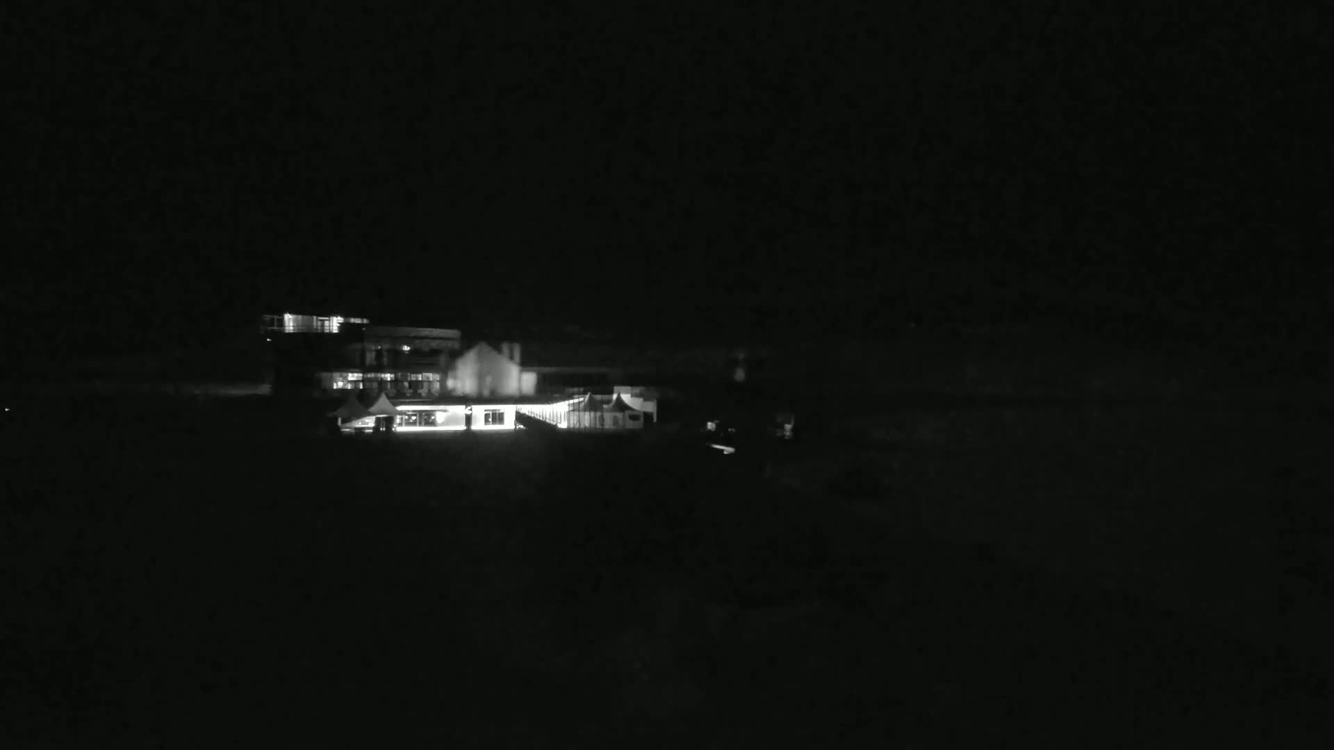 A dimly lit building complex is visible at night under a dark sky.