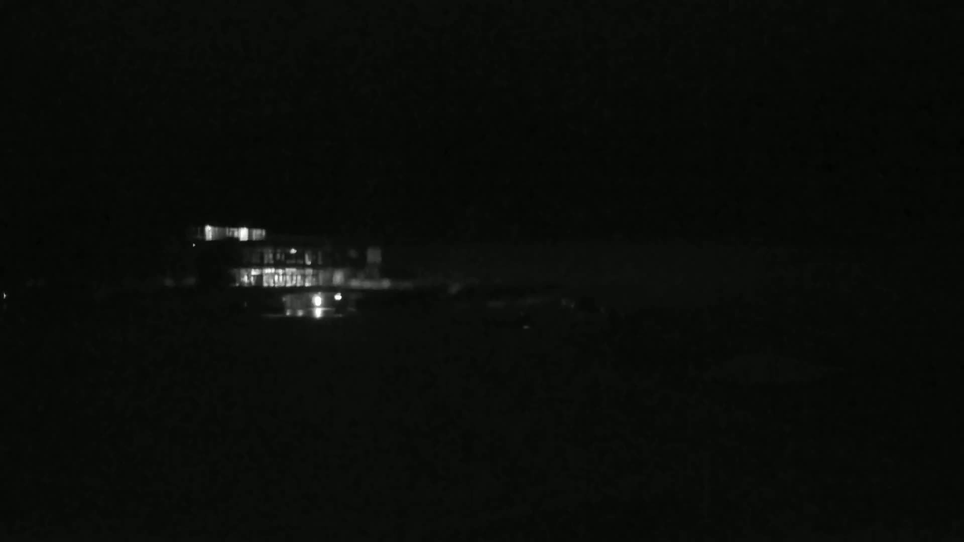 A dimly lit building is visible at night, across a dark body of water.