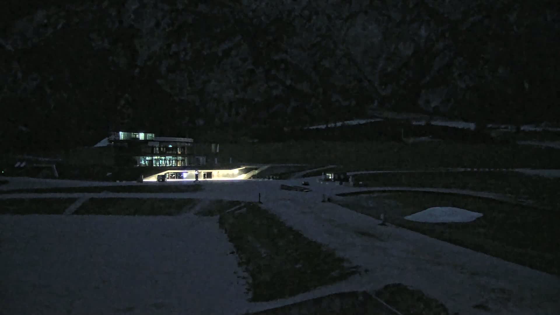 A lit building sits on a snow-covered landscape at night.