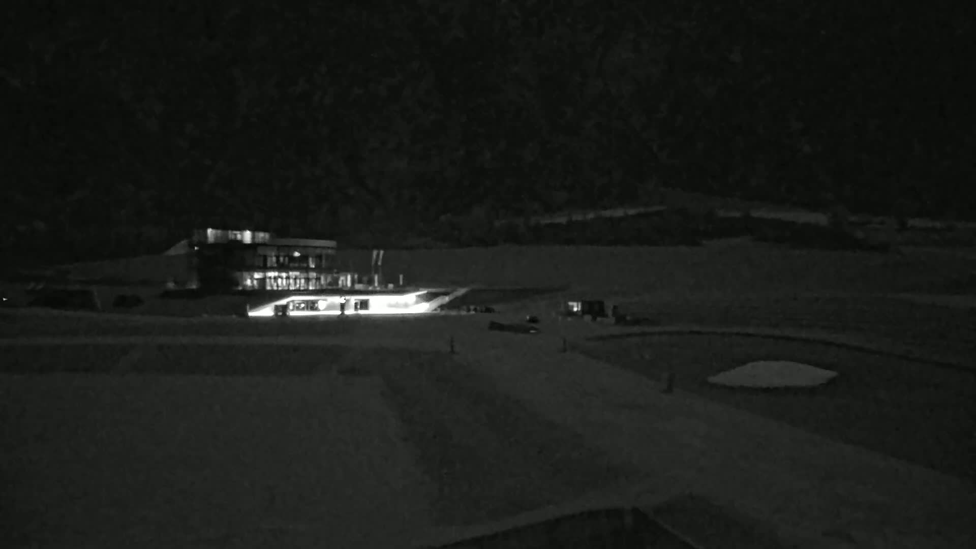 A brightly lit building sits on a snow-covered landscape at night.
