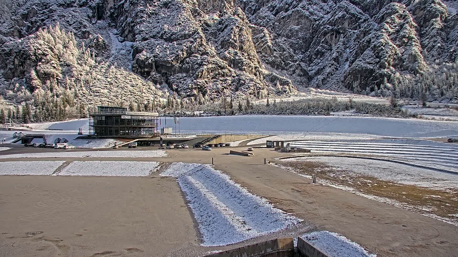 A very dark and blurry grayscale image taken at night reveals a distant building with glowing windows and a bright horizontal light source at its base.