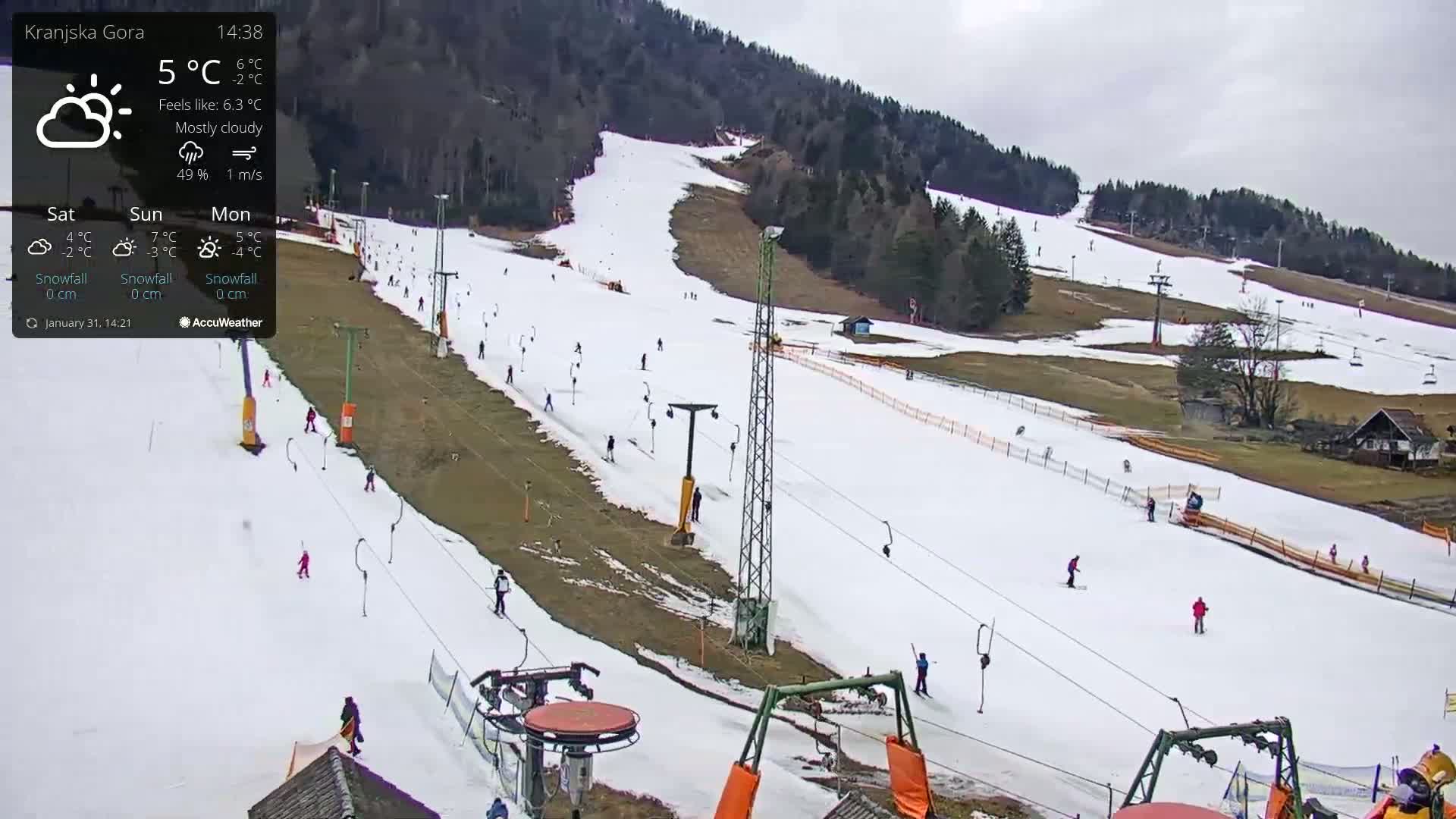 A mostly cloudy ski slope with several skiers and chairlifts visible, under a mostly cloudy sky.