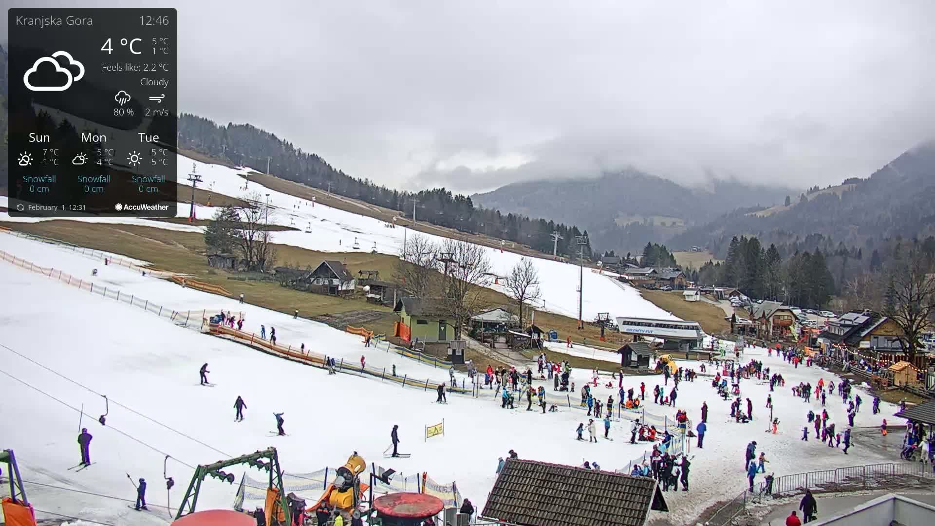 A snow-covered ski slope with many people skiing and playing in cloudy weather.