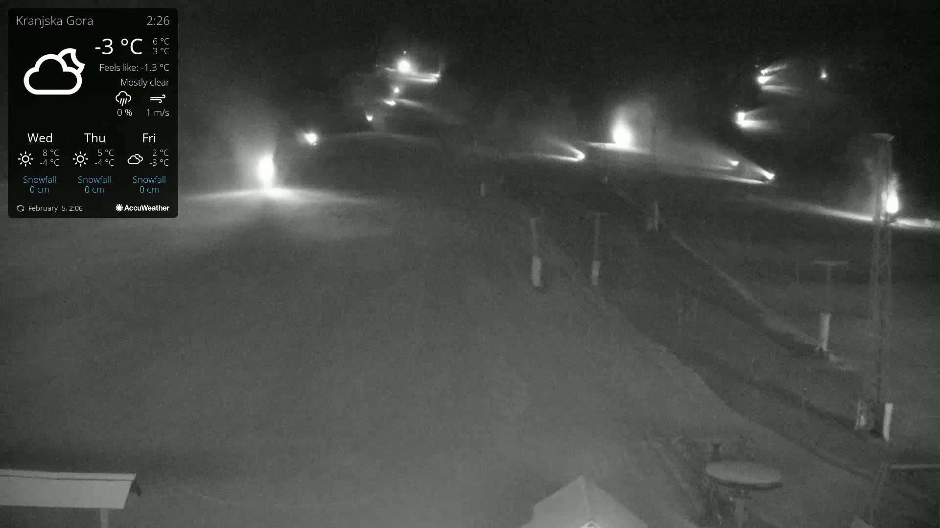 A nighttime, mostly clear view of snow cannons operating on a snow-covered slope.