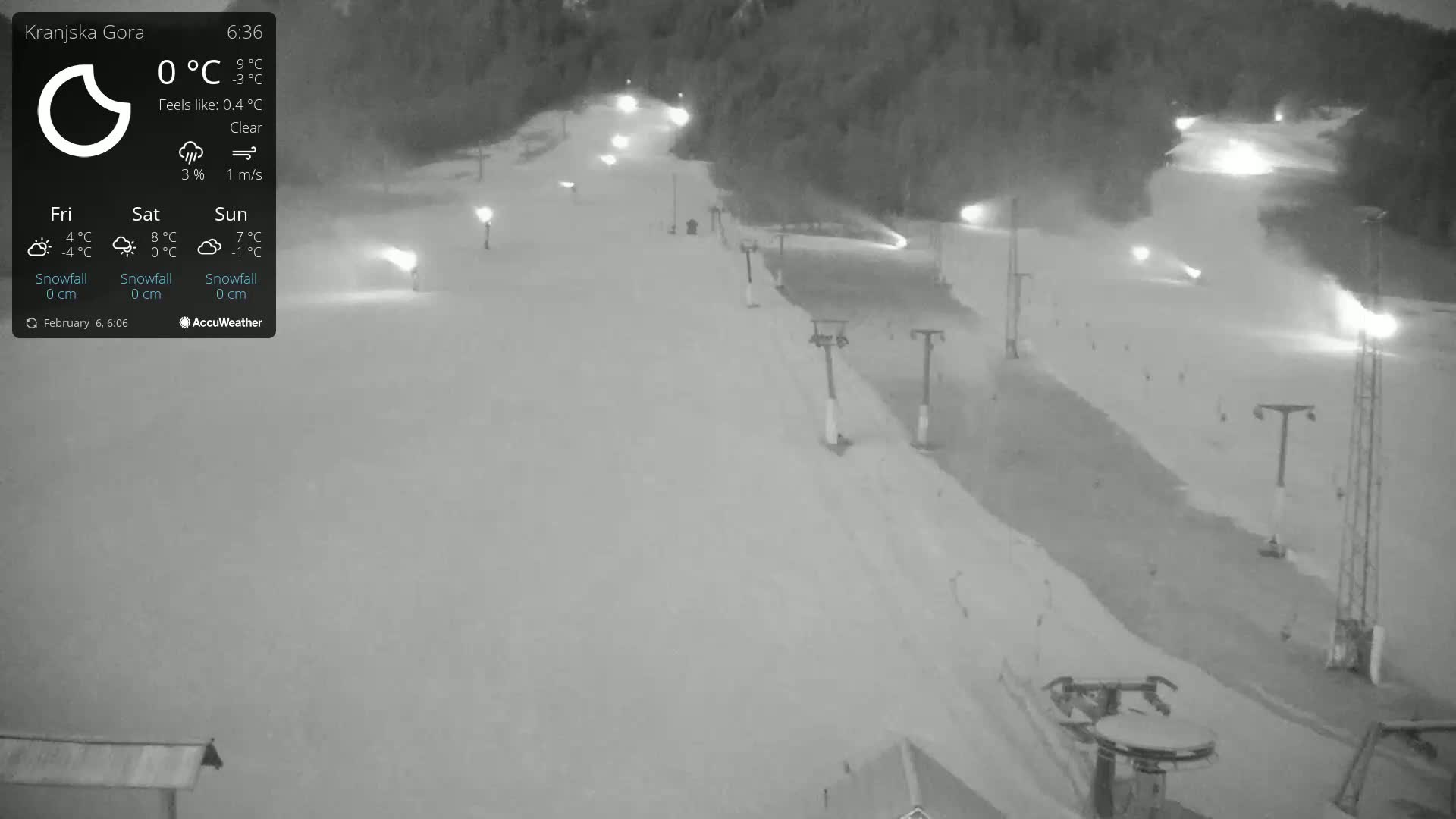 A nighttime, clear-weather view of a snow-covered ski slope illuminated by lights, with ski lifts visible.