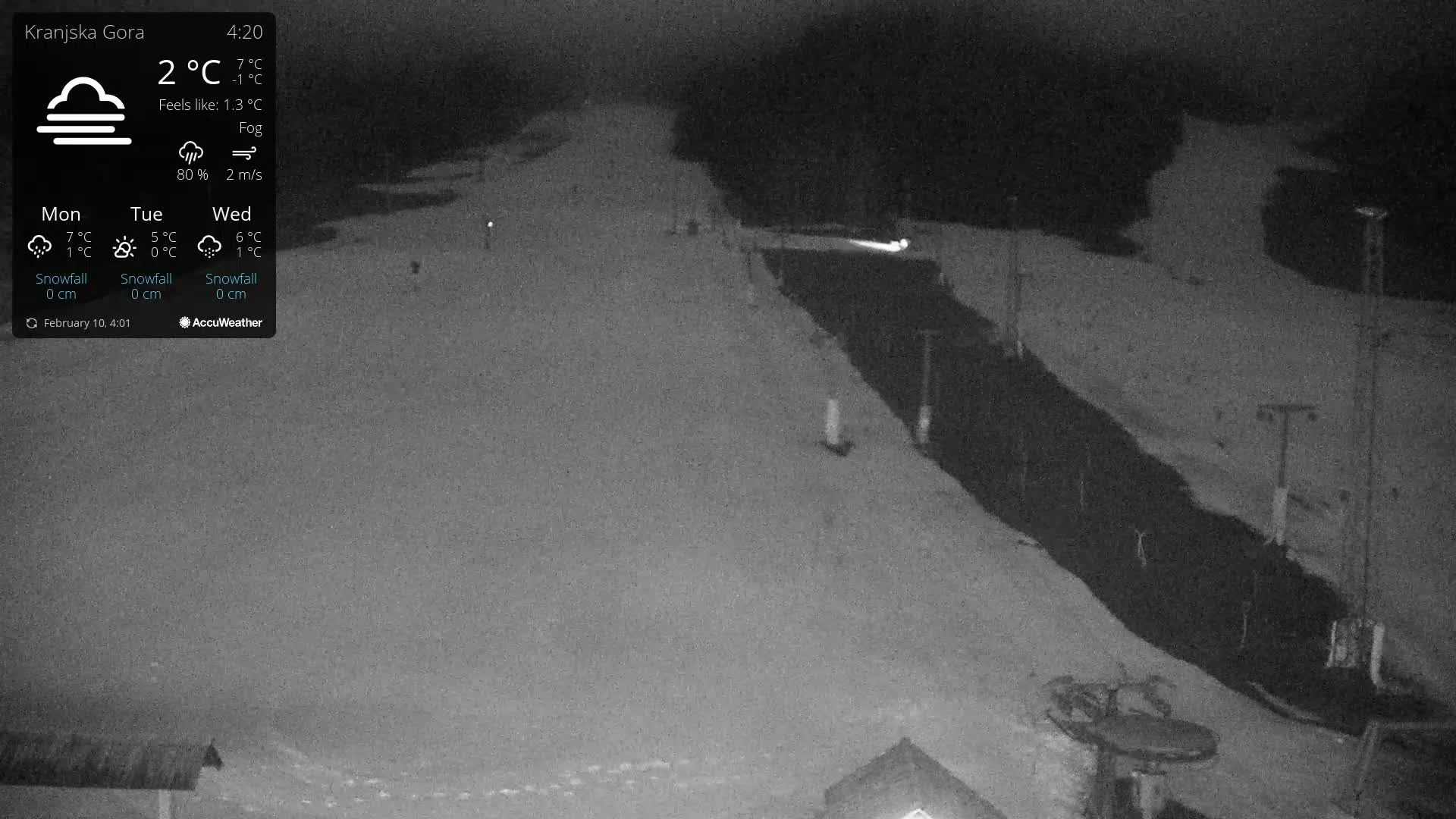 A snow-covered ski slope is visible at night under foggy conditions.