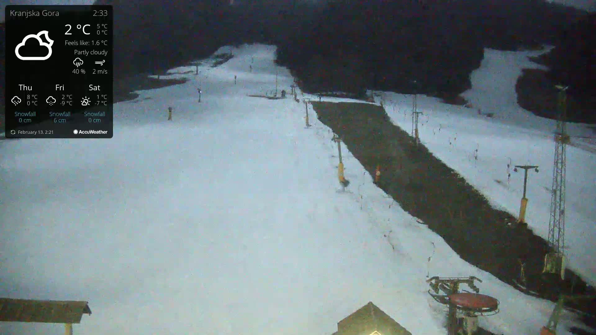 A snow-covered ski slope with a ski lift under partly cloudy conditions.