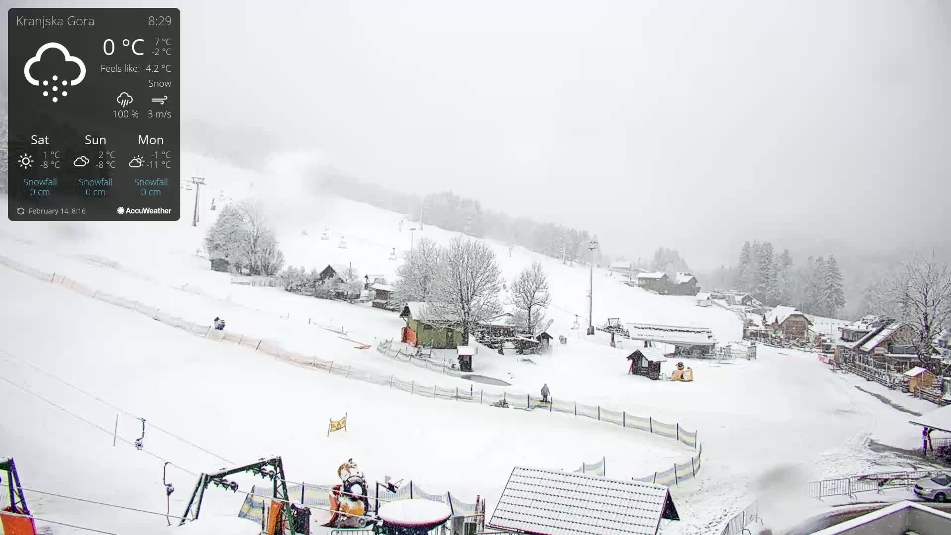 A snow-covered ski resort with several buildings and ski lifts under heavy snowfall.