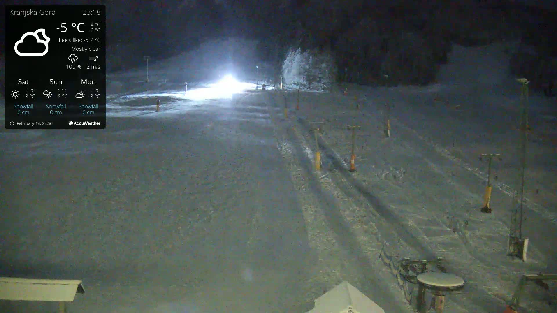A mostly clear night at a snow-covered ski resort, illuminated by bright lights.