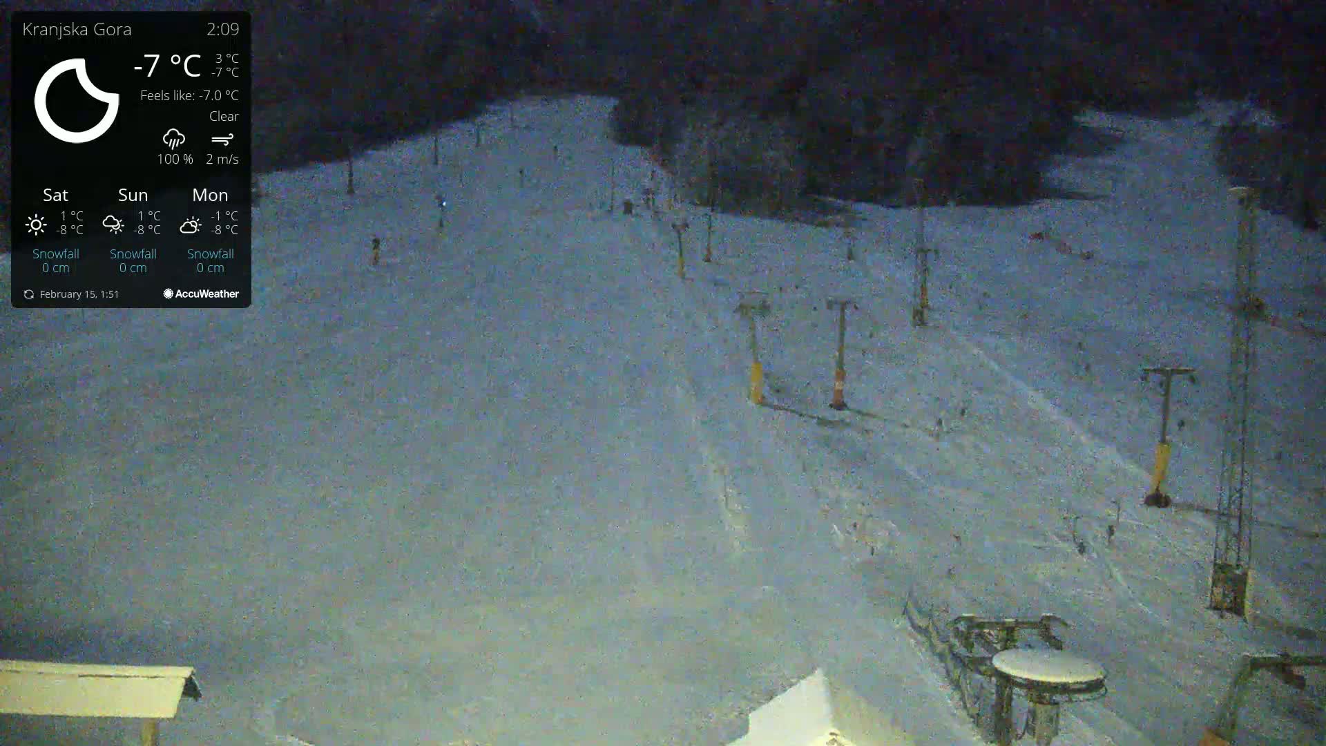 A nighttime, clear view of a snow-covered ski slope with several ski lifts visible under a clear sky.