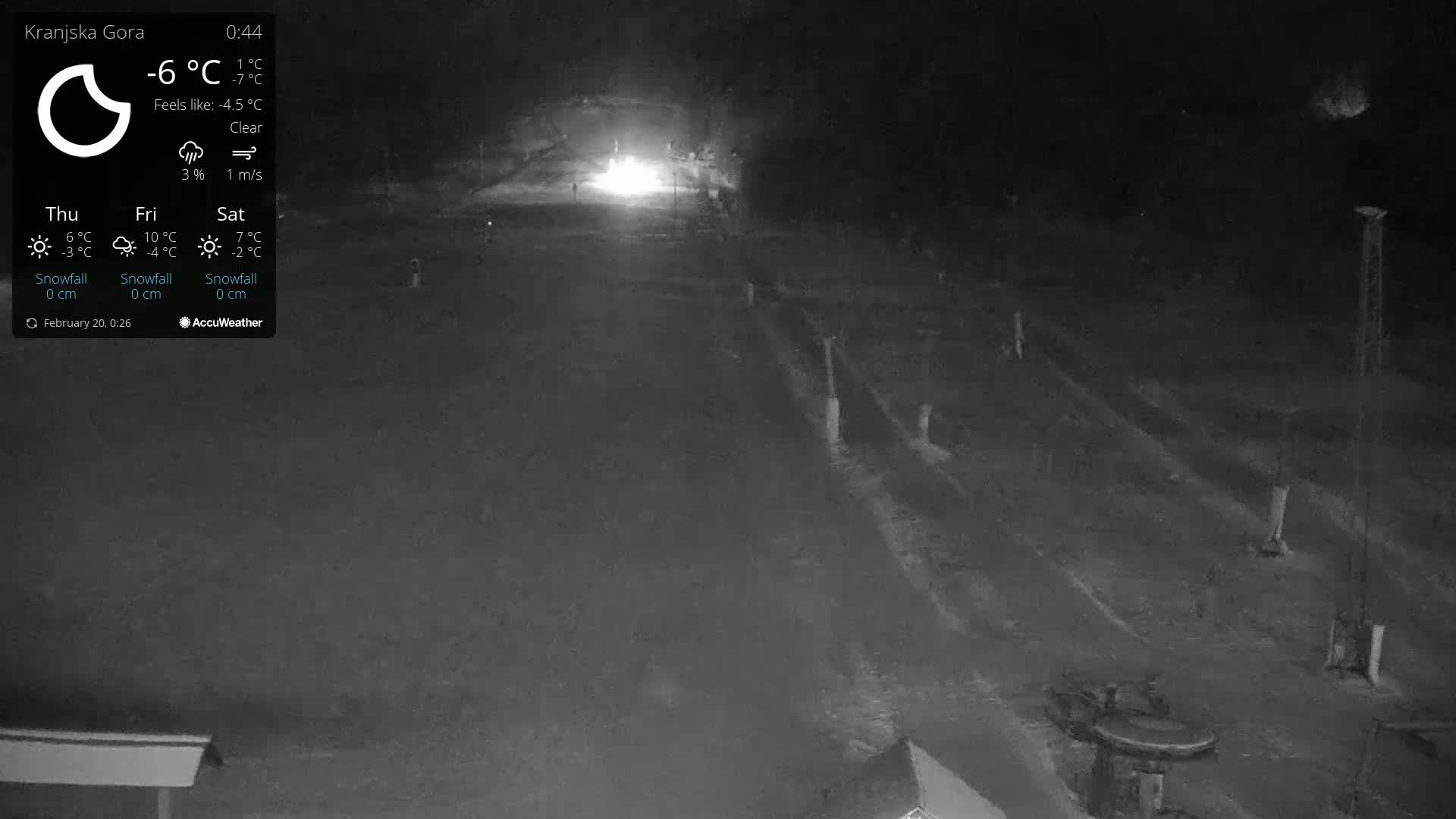 A nighttime, clear view of a snow-covered road or path, illuminated by headlights of a vehicle in the distance.