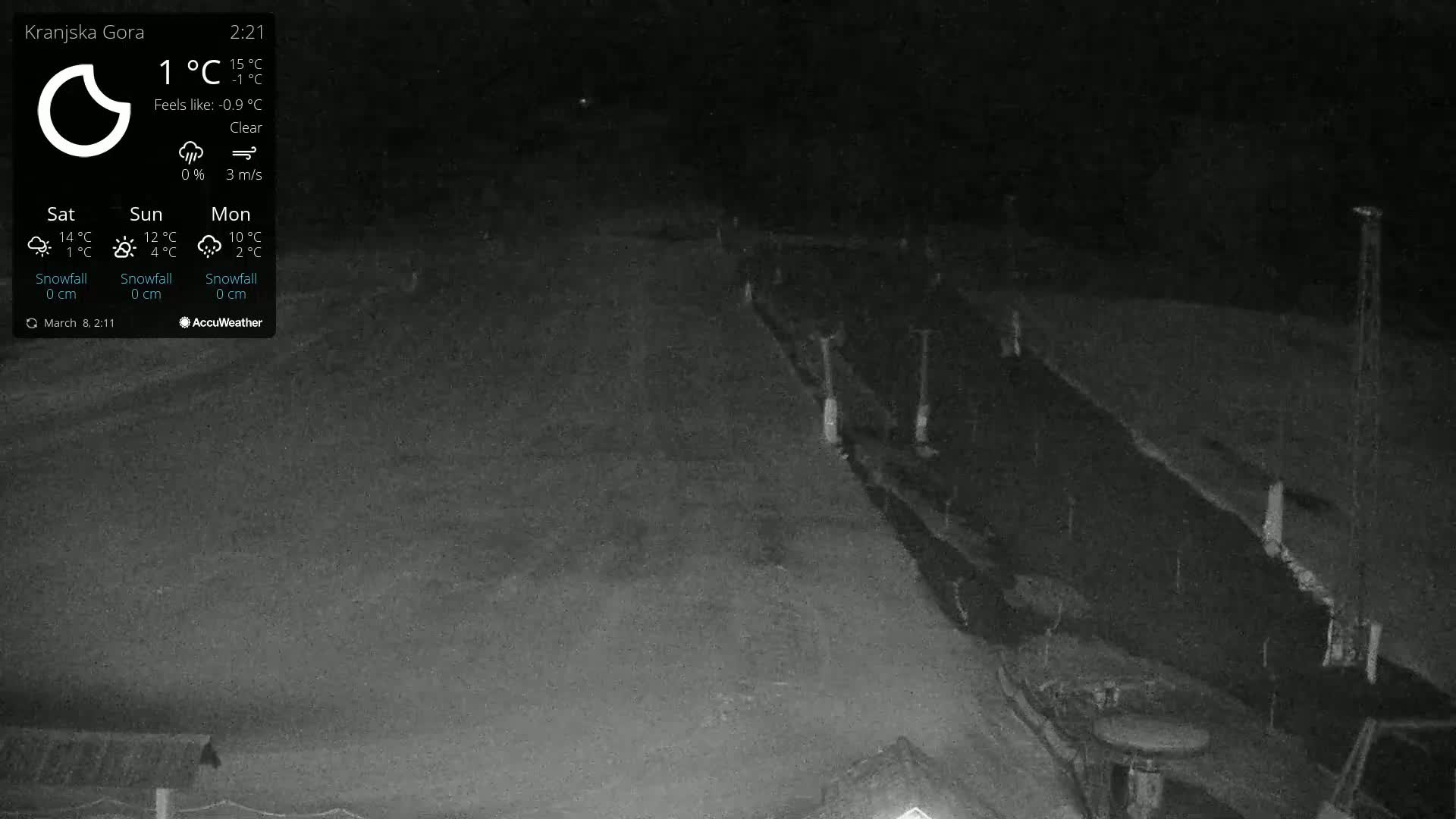 A nighttime, clear view of a snow-covered area with a fence and some structures in the lower right corner.