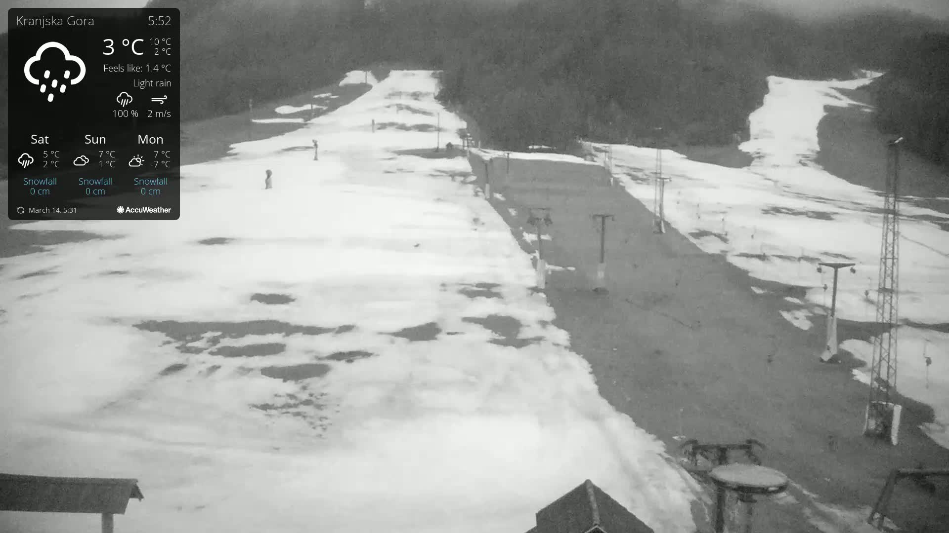 A snow-covered ski slope with light rain is visible, with a few ski lifts and a dark wooded area in the background.