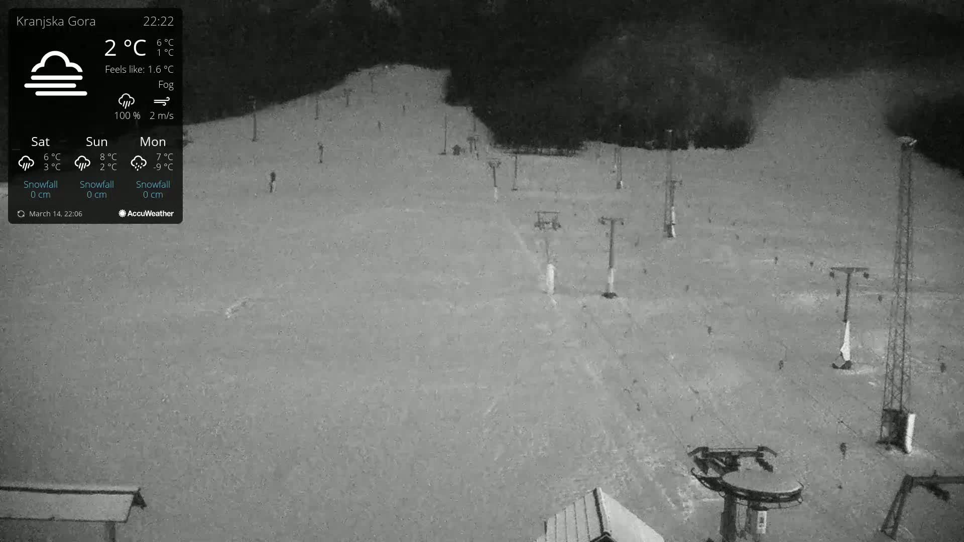 A nighttime, foggy view of a snow-covered ski slope with several chairlifts visible.