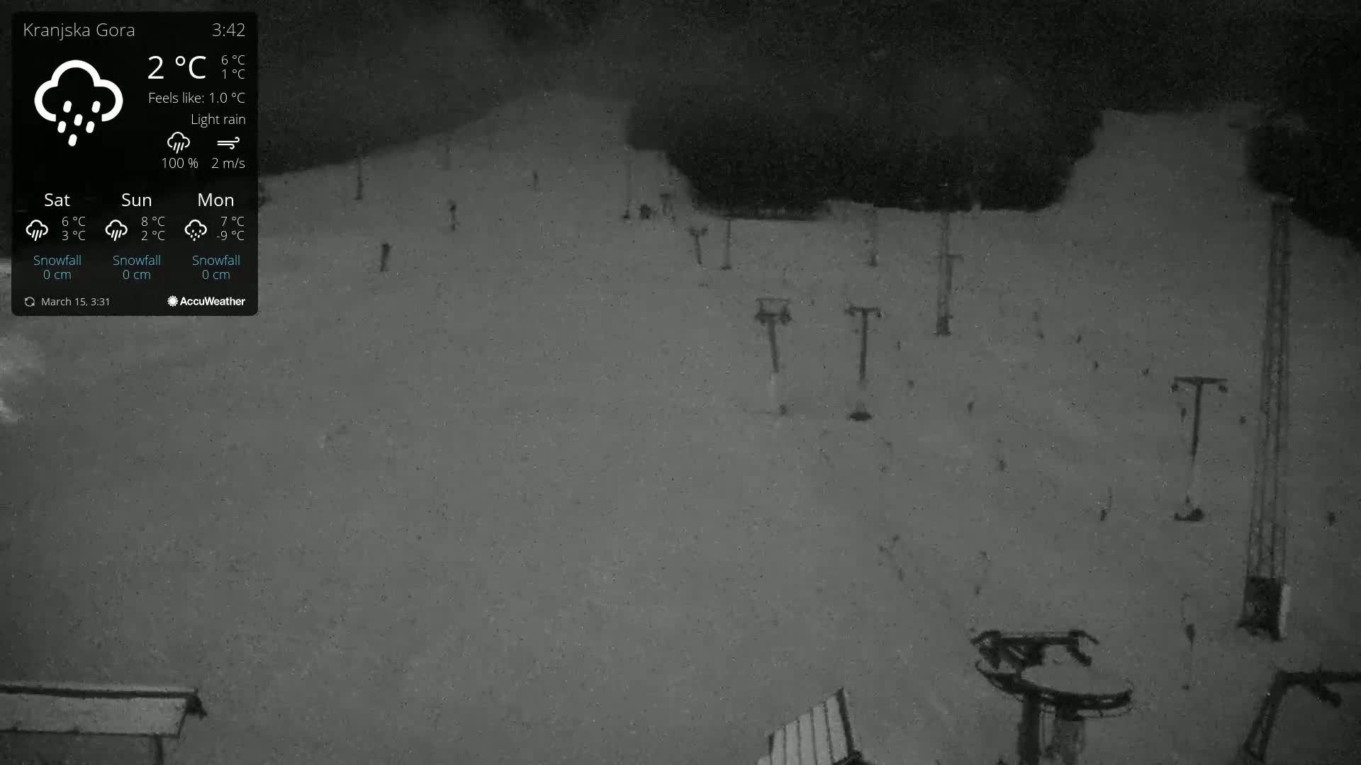 A nighttime, snowy ski slope with several ski lifts is visible under light rain.