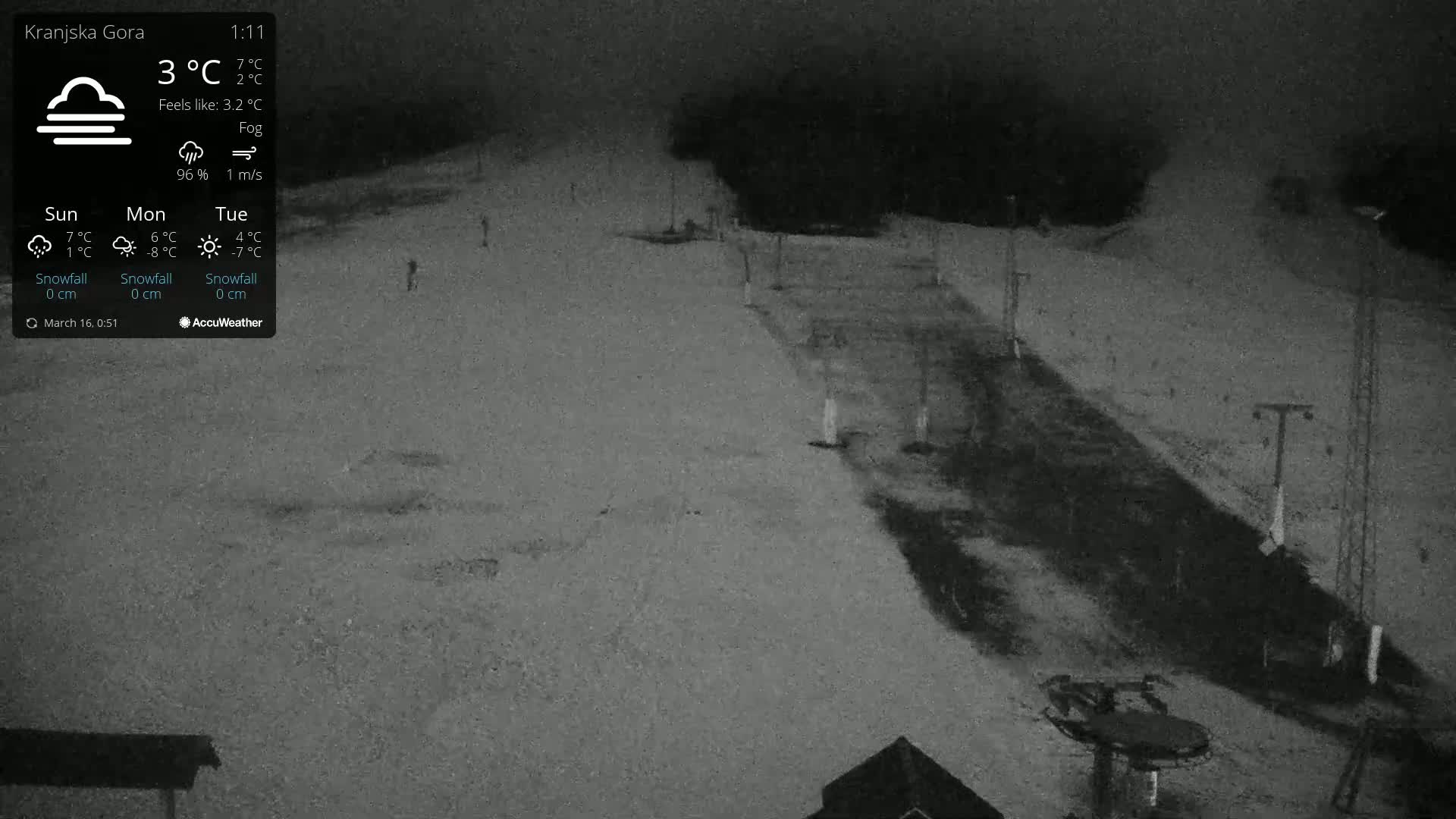 A nighttime view of a snow-covered ski slope under foggy conditions.