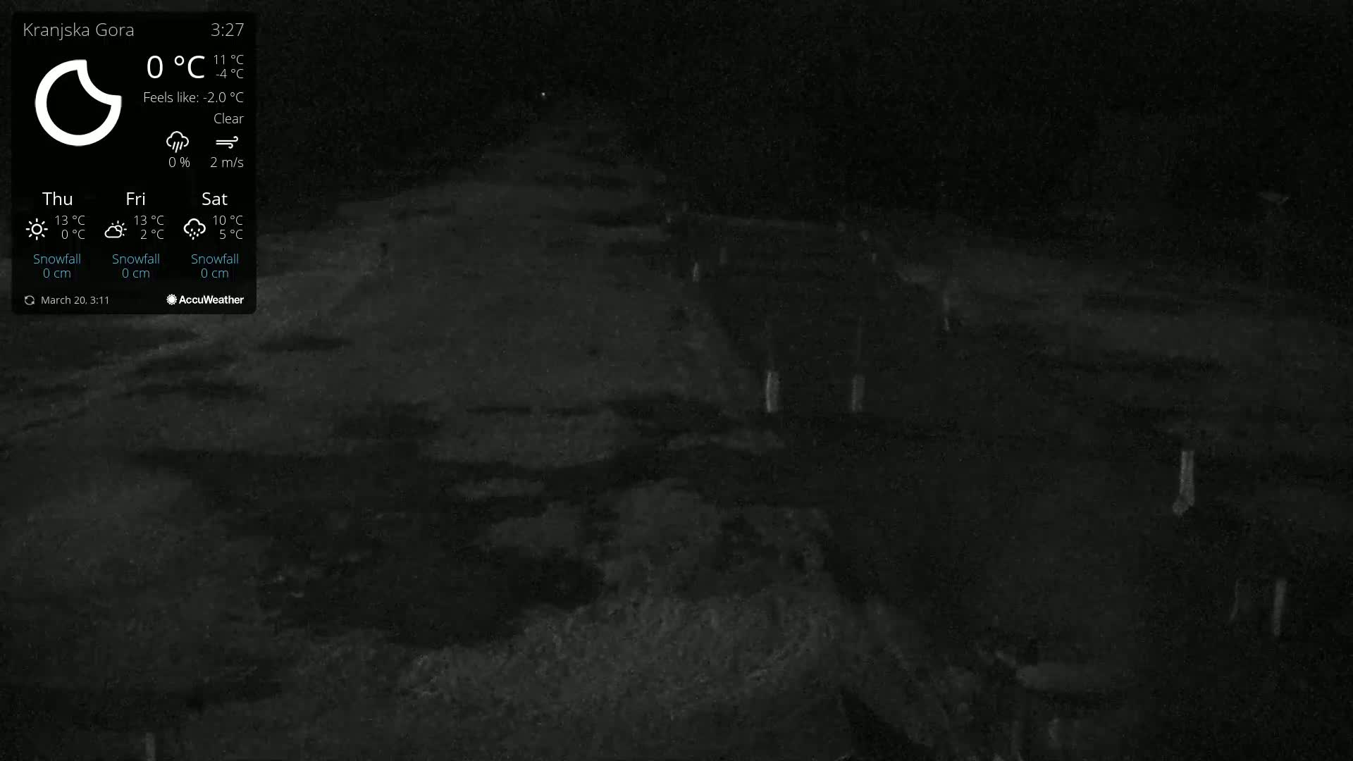A dark, nighttime view of a clear, paved area with some indistinct objects and light posts visible under a clear sky.