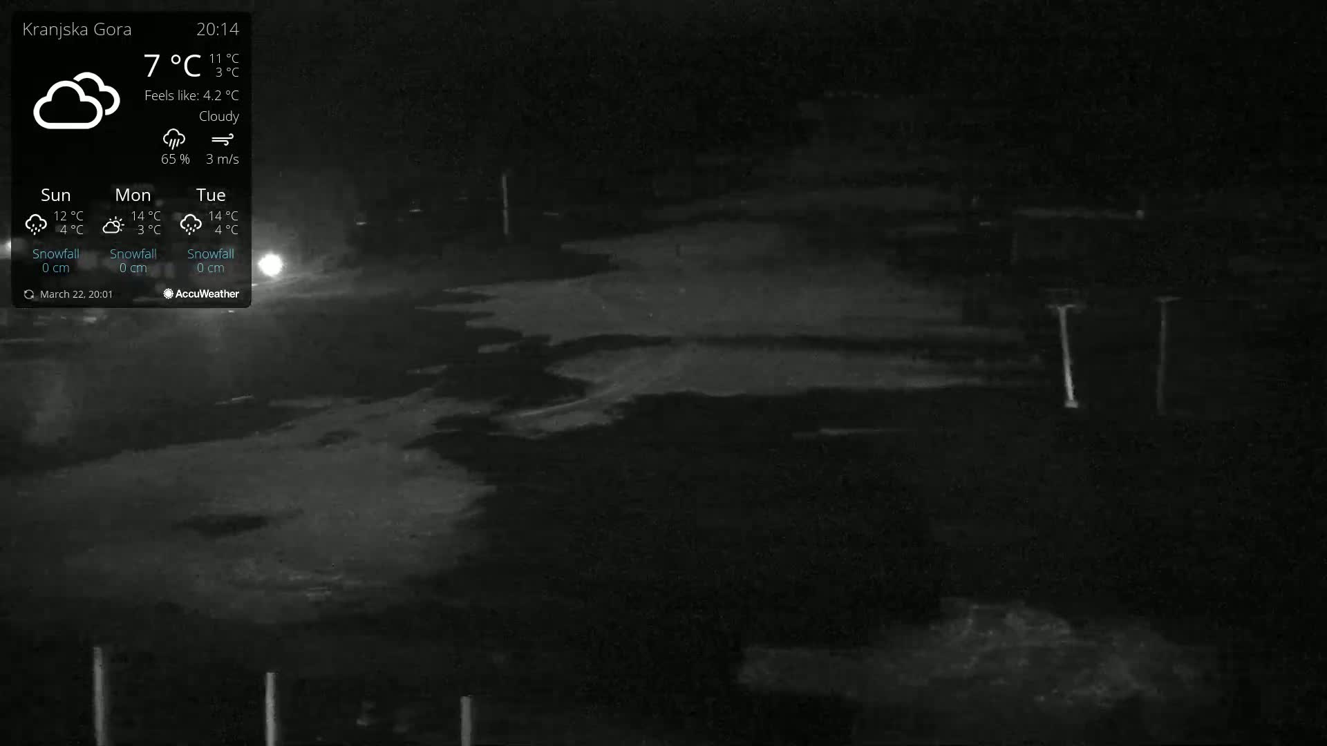 A nighttime, cloudy outdoor scene shows a dark, mostly empty area with a few indistinct objects and light poles under a sky barely visible due to the darkness.