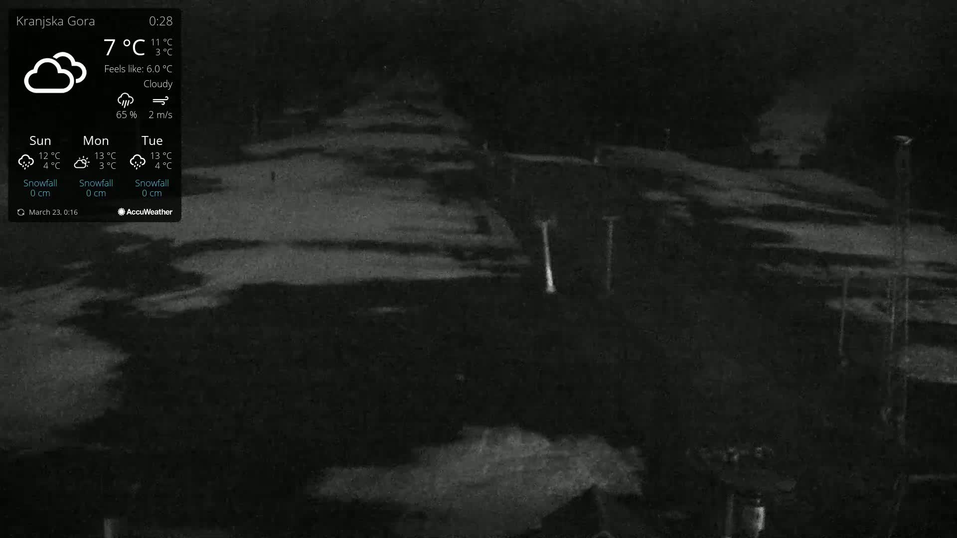A nighttime, cloudy scene shows a snow-covered area with several tall, thin structures under low-light conditions.