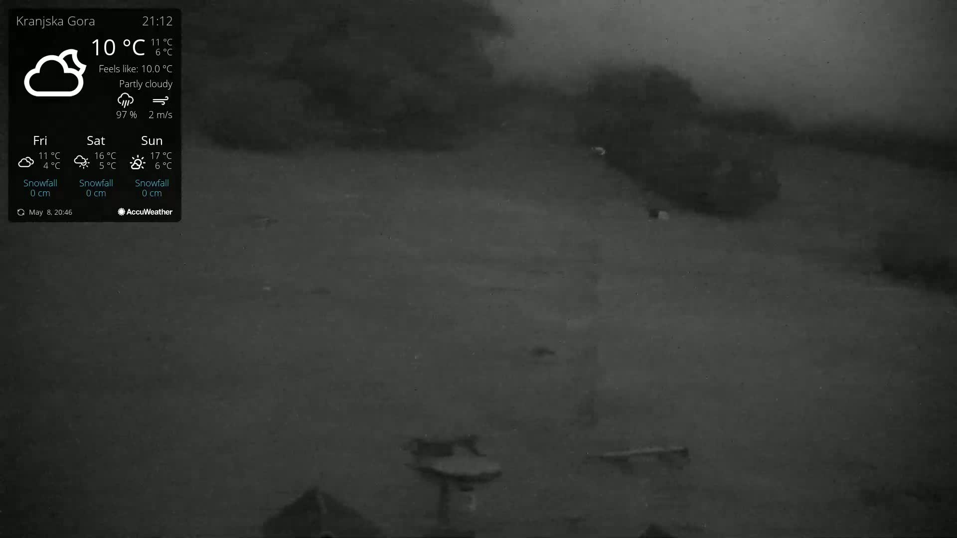 A dark, partly cloudy night scene shows a flat expanse of land with some indistinct objects and vegetation under a hazy sky.