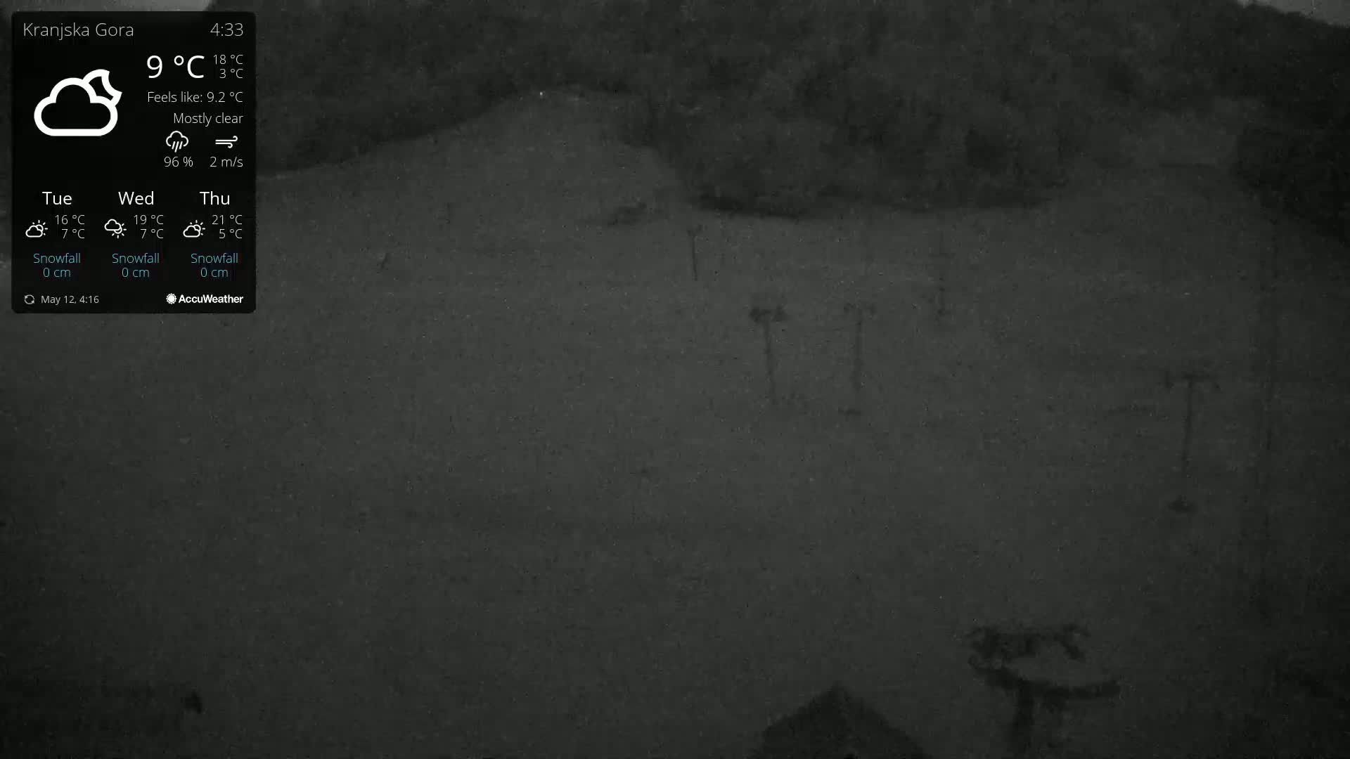 A mostly clear, nighttime view of a snow-covered landscape with several poles visible in the distance under a 9°C temperature.