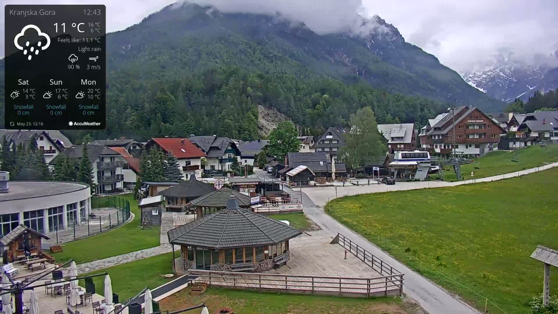 A light rain falls on a village nestled in a valley between mountains.
