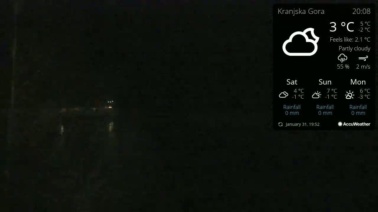 A dark, nighttime outdoor scene under partly cloudy skies shows a dimly lit area with some faint lights visible in the distance.