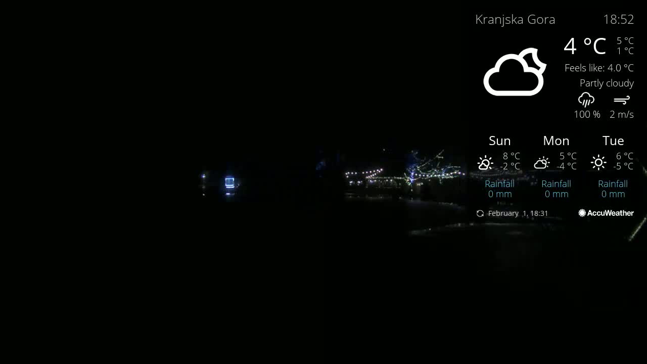 A nighttime, partly cloudy scene shows a dimly lit area with strings of lights visible in the distance under a 4°C temperature.