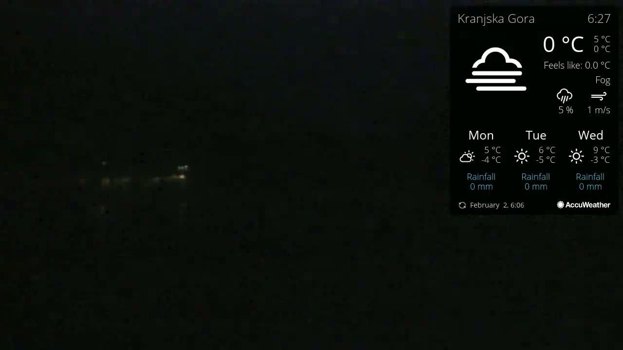 A dark, foggy nighttime scene with faintly visible lights in the distance.