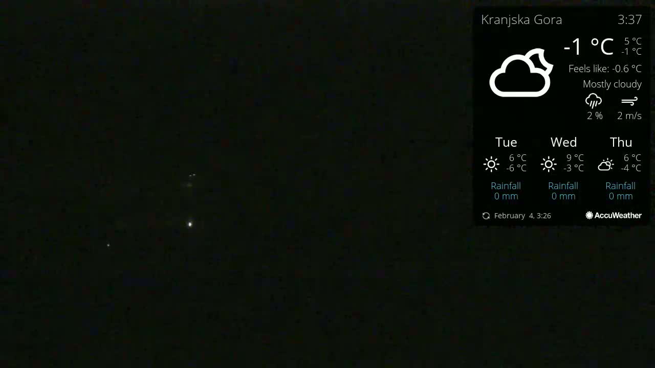 A mostly cloudy night sky with a few distant lights visible, the temperature is -1°C.
