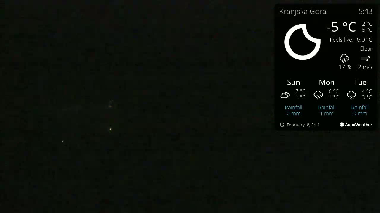 A dark nighttime scene with a few faint lights visible in the distance under clear skies.